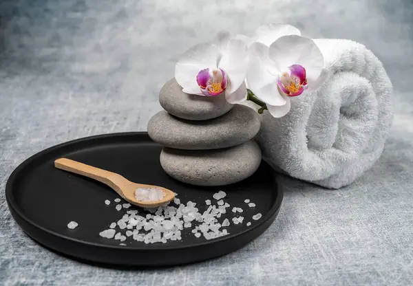 Beyaz ve siklamen çiçekleri, spa taşları ve dokulu havluyla kaplıca dekorasyonu