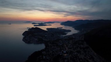Eski kasaba Dubrovnik 'in muhteşem panoramik klibi, aydınlatılmış caddeler, binalar ve gün batımında tekneleri olan marina..