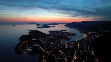 Eski kasaba Dubrovnik 'in muhteşem panoramik klibi, aydınlatılmış caddeler, binalar ve gün batımında tekneleri olan marina..