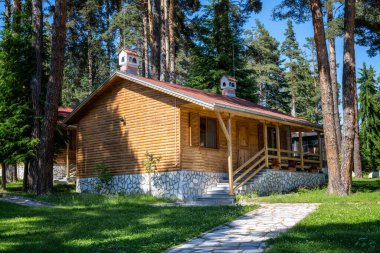 Bulgaristan 'ın Bansko kenti yakınlarındaki antik ağaçların arasında güzel bir dağ köyünde verandası olan tek katlı ahşap bir bungalov.