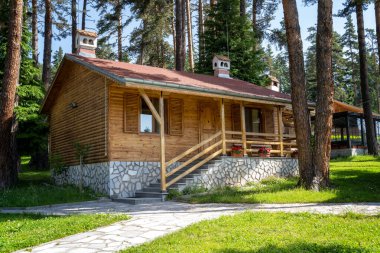 Bulgaristan 'ın Bansko kenti yakınlarındaki antik ağaçların arasında güzel bir dağ köyünde verandası olan tek katlı ahşap bir bungalov.