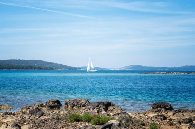 Hırvatistan 'ın Dalmaçya kentinin Primosten kenti yakınlarındaki Adriyatik Denizi sularındaki bir yatın uzak manzarası.