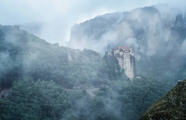 stock image Amazing panoramic view of the cliffs in the Meteora valley and the monasteries mysteriously shrouded in mist and low clouds near Kastraki, Greece.