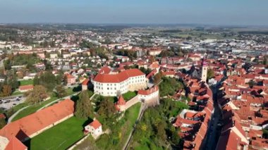 Slovenya 'daki Drava nehri boyunca Ptuj eski kasabasının evlerinin üstündeki tepede güzel Ptuj şatosunun yer aldığı hava videosu