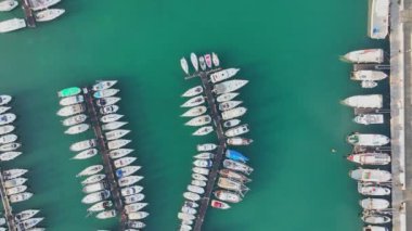 Slovenya 'nın İzola kentindeki marinada sıra sıra park etmiş yat ve teknelerle hava manzarası. Çapalı teknelerle üst görünüm.