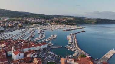 Eski kenti ve kırmızı çatıları olan binaları, ana gezinti alanı, Adriyatik sahil kıyısı Slovenya 'da botları olan marinaları olan manzaralı Izola kasabasının hava panoramik videosu.