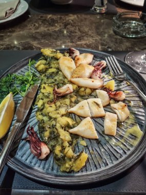 Karadağ 'da geleneksel bir deniz ürünleri restoranında servis edilen patates püresi ve ıspanak garnitürlü ızgara bebek kalamar. Masada ızgara kalamar..