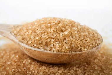 Beyaz arka planda kahverengi şekerli ahşap kaşık