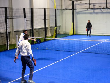 Bairo, İtalya - Aralık 2020: Erkekler kapalı bir sahada Padel oynar. Padel tenis, squash ve badminton unsurlarını birleştiren bir raket sporudur.