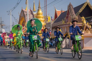 Chiang Mai, Tayland - 20 Ocak 2023: Geleneksel kostümler içinde güzel şemsiyeler taşıyan ve bisiklete binen güzel kadınlar San Kamphaeng, Bosang şemsiye festivali.