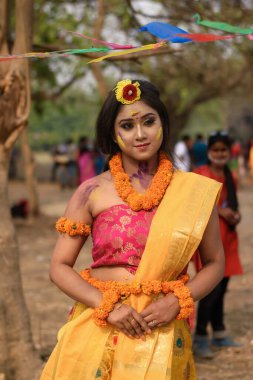 Portrait of beautiful happy young Indian woman with spring festive make up celebrating Holi with powder colours in Kolkata on March 2021