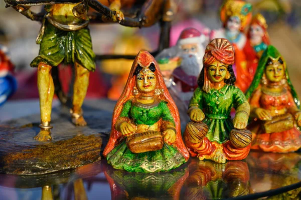 Beautiful handmade dolls of miniature folk musicians performing in a band of classical Indian music is displayed in a shop for sale in blurred background. Indian art and handicraft.