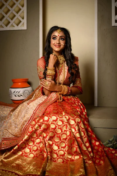 Portrait of very beautiful young Indian lady in luxurious costume with makeup and heavy jewellery posing fashionable in studio lighting indoor. Religious Lifestyle Festive Fashion.
