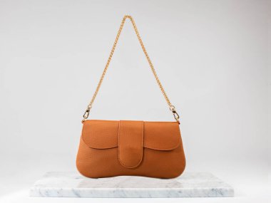 Şatafatlı kadınların çantası. Beyaz arka planda, mermer zeminde, lüks kahverengi deri bir çanta. Altın zincirli bir çanta. Kadınlar için şık aksesuarlar. ön taraf