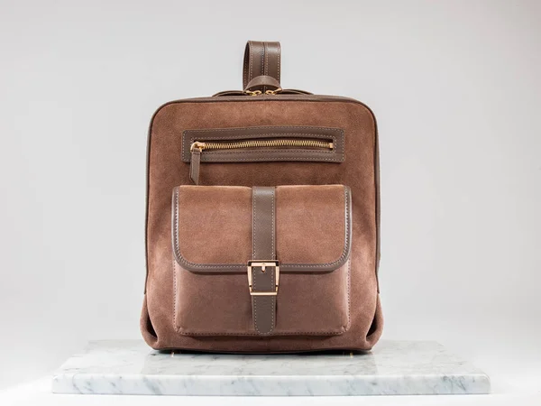 Luxury suet backbag, unisex backbag. Luxury, brown leather and suet backbag on white background, on marble floor. A elegant bag is see from front side. Fashionable trendy.