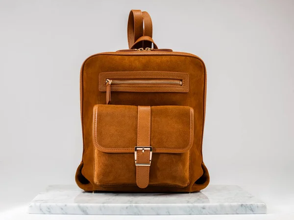 Luxury suet backbag, unisex backbag. Luxury, orange leather and suet backbag on white background, on marble floor. A elegant bag is see from front side. Fashionable trendy.