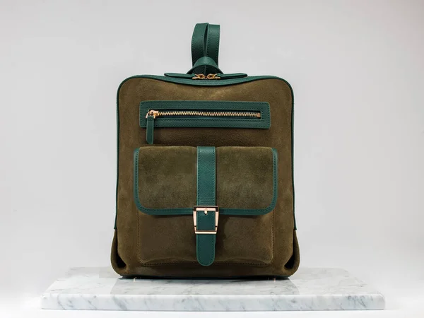 Luxury suet backbag, unisex backbag. Luxury, green leather and suet backbag on white background, on marble floor. A elegant bag is see from front side. Fashionable trendy.