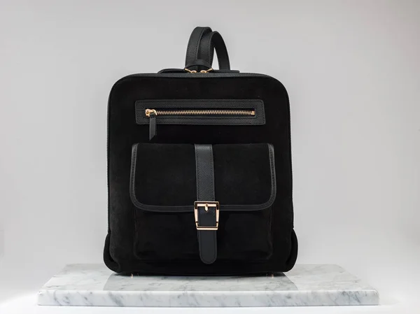 Luxury suet backbag, unisex backbag. Luxury, black leather and suet backbag on white background, on marble floor. A elegant bag is see from front side. Fashionable trendy.