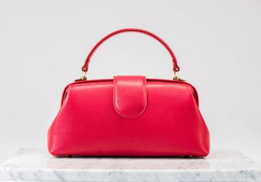 Şatafatlı kadınların çantası. Beyaz arka planda, mermer zeminde lüks kırmızı deri bir çanta. Zarif bir çanta. Moda modası. 