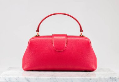 Şatafatlı kadınların çantası. Beyaz arka planda, mermer zeminde lüks kırmızı deri bir çanta. Zarif bir çanta. Moda modası. 
