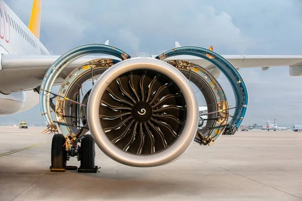 Motosikletli modern bir ticari uçağın jet motoru havaalanı apronunda bakım için açık. Gündüz vakti turbofan motoru ve iniş takımlarının detaylı görüntüsü.