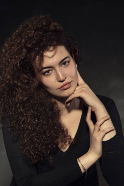 Genç, güzel, beyaz tenli ve kızıl saçlı bir kızın portre fotoğrafları. Kıvırcık saçlı güzel bir kadının portresi. Siyah arkaplanda stüdyo fotoğrafı