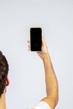 Stüdyoda ve beyaz arka planda akıllı telefonu tutan adam, reklam ve görselleri yerleştirmek için akıllı telefonun ekranı boştur.. 