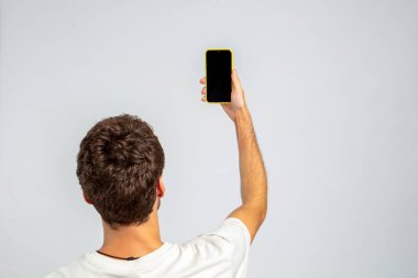 Stüdyoda ve beyaz arka planda akıllı telefonu tutan adam, reklam ve görselleri yerleştirmek için akıllı telefonun ekranı boştur.. 