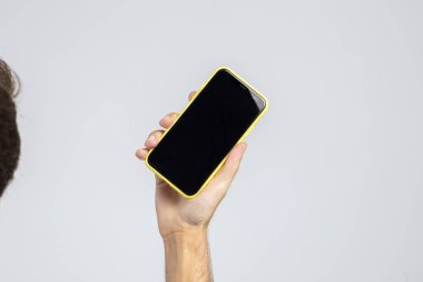 Elinde akıllı telefon tutan bir adam, stüdyoda ve beyaz arka planda, akıllı telefonun ekranı boş, reklamları ve görüntüleri yerleştirmek için. Yüksek çözünürlüklü resim