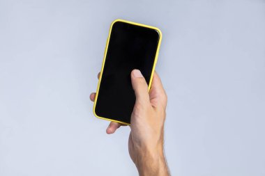 Sağ eliyle akıllı telefonu tutan ve baş parmağıyla ekranda çalışan bir adamın eli. Telefon ekranı boş ve siyah, reklam ya da resim koymak için uygun. Beyaz arkaplan