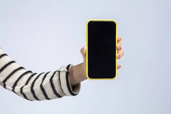 女人的手拿着一个白色背景的智能手机手机屏幕是空白和黑色的 适合放置广告或图像 在白色背景下隔离高质量的摄影棚拍摄 — 图库照片