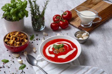 Geleneksel bir aroma, kremalı domates çorbası. Küplere kesilmiş çıtır ekmekler. Biberiye, nane, domates, sarımsak ve kremayla süslenmiş bir masa.