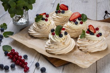 Orman meyveleri ve çileklerle süslenmiş kremalı tatlı. Kremalı pasta, yumurta beyazı ve pudra şekerinden yapılan köpüklü bir kurabiye türüdür. Fransızca 