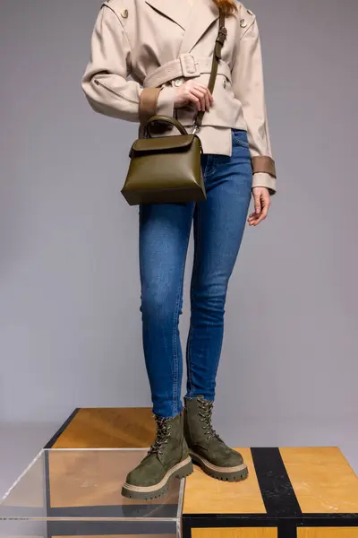 Kvinna Beige Trenchcoat Blå Jeans Med Mörkgrön Läderväska Och Stövlar Stockfoto