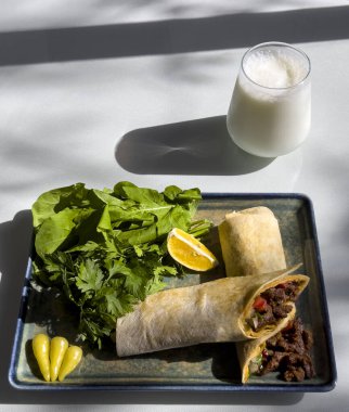 Traditional Turkish Cuisine, Tantuni Kebab, Famous Mersin Tantuni. Tantuni dish taken in sunlight at a restaurant. Meat wrap with arugula, parsley, lemon and ayran. Top wiev clipart