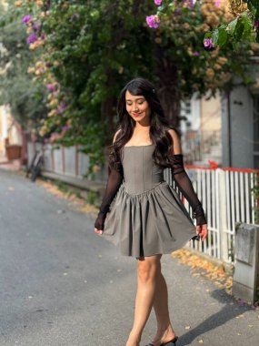 Mutlu kız hareket halinde, yürüyor ve kameraya poz veriyor. Genç, esmer, dışarıda şık kıyafetler giyen güzel bir kız.