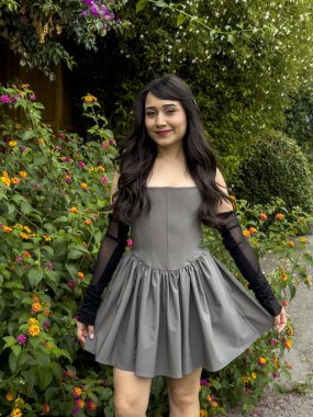 Kameraya çeşitli pozlarda poz veren tatlı bir kız. Çiçeklerin ve yeşilliklerin önünde güzel, esmer bir kız..