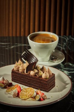 Bir parça çikolatalı kek ve koyu arka planda bir fincan kahve.