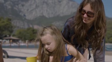 Genç bir aile, anne, baba ve iki çocuk sahilde eğleniyor. Bir kız ve bir oğlanla mutlu bir aile, yaz tatilinde harika vakit geçiriyorlar, kumda oynuyorlar. Tatil ve aile kavramı