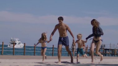 Genç bir aile sahilde koşuyor ve eğleniyor. Bir kız ve bir oğlanla mutlu bir aile yaz tatilinde harika vakit geçiriyor. Tatil ve aile kavramı