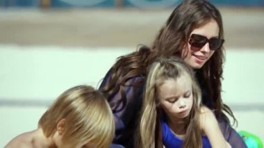 Genç bir aile, anne ve iki çocuk sahilde eğleniyor. Bir kız ve bir oğlanla mutlu bir aile. Çocuklar ve anne kumda oynuyor. Yaz tatlısı konsepti