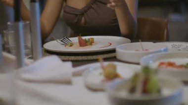 Özel olarak hazırlanmış et yemeği, masada servis edilir ve ilk lokma için kesilir. Seksi ve güzel bir kadın masada sohbet ediyor ve yemek yiyor. Yüksek kalite yakın çekim ve hareket eden kamera.