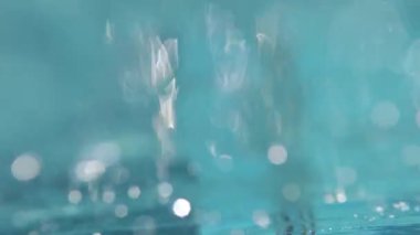 Su altı yansımalarında kamera ve bir kişi, renkli mayo giymiş genç bir kız suyun altında yüzmeye hazırlanıyor. Su altı kabarcıkları, yansımalar, turkuaz rengi ve yüksek kaliteli çekim.