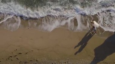 Mutlu genç bir çift kıyı boyunca el ele koşar, dalgalar ayaklarının etrafını sarar. Hava aracı sahilde kaygısız aşkı, özgürlüğü ve yaz neşesini yakalıyor..