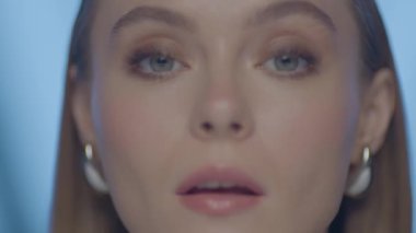 Açık tenli, mavi gözlü ve ince makyajlı, yumuşak stüdyo ışıklarıyla yakalanmış bir kadının sinematik makro güzellik portresi..