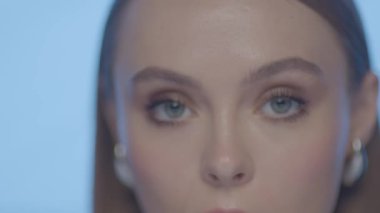 Doğal makyajlı ve açık tenli bir kadının yakın çekimi, çeşitli göz yönleri ve hafif stüdyo aydınlatmasında ince ifadeler sergiliyor.