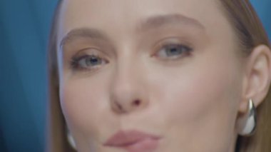 Açık tenli, mavi gözlü ve ince makyajlı yumuşak stüdyo ışıklarıyla yakalanmış genç bir kadının sinematik makro güzellik portresi. Değişen Işık ve Evrimleşen İfadesiyle Kadının Dinamik Yakın Çekimi