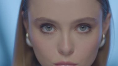 Değişen Işıklı ve Evrimleşen İfadesiyle Kadının Dinamik Yakın Çekimi. Açık tenli, mavi gözlü ve ince makyajlı, yumuşak stüdyo ışıklarıyla yakalanmış bir kadının sinematik makro güzellik portresi..