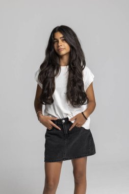 Son moda genç kız elleri ceplerinde poz veriyor, günlük beyaz tişört ve siyah kot etek, havalı şehir stüdyo resmi..