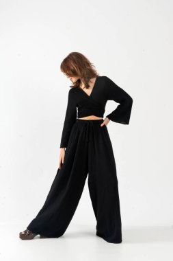 Siyah ambalajlı manken üst ve geniş paçalı pantolonlar şık bir şekilde poz veriyor..
